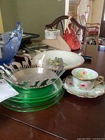 Uranium glass plates, steel basket with animal cutouts, Limoges cup and saucer, and figurine on table showing lot contents