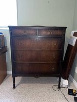 Front view of the vintage wooden dresser showing its dark finish and metal ring handles on drawers.