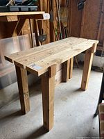 Photo showing front angle of homemade wooden work bench with natural wood planks in garage setting.