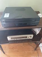 Full view of Yamaha CDC-697 compact disc player on top shelf and Luxman receiver on bottom shelf of wooden furniture