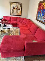Front angle view of the custom red microsuede sectional couch situated around a glass coffee table, showing plush cushions, the corner piece, and daybed section.
