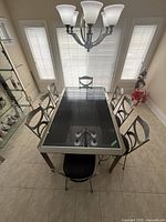 Full overview of the dining table with metal frame and tinted black glass top, showing size and seating for six chairs.