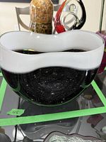 Front angle showing the black base with starry speckle effect and white wavy rim on top of the decorative glass bowl.