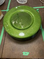 Stack of green glass serving chargers showing top textured surface and round shape