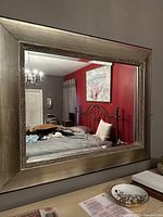 Full front view of large rectangular wall mirror mounted on wall above table, showing room reflection.