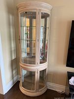 Full view of light oak curved display cabinet with glass front and sides, with mirrored back and multiple glass shelves inside.