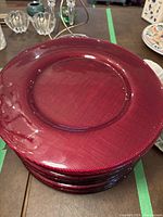 Close-up top-down image of stacked vibrant red glass chargers showing texture and color.