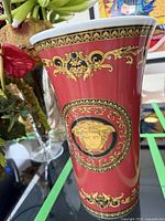 Front view of red porcelain vase with gold Medusa and floral motifs