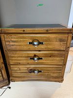 Front view of the wooden small side dresser showing three drawers with metal handles.