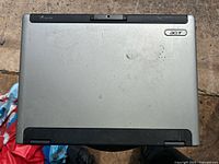 Closed view of the silver Acer Aspire laptop showing wear and dirt marks on the lid