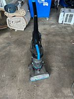 Front upper view of the black and blue Bissell PowerForce Helix upright vacuum cleaner showing handle, dust container, and cleaner head with turbopass brush.