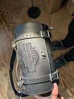 Front side showing embossed Harley-Davidson logo, snap closure, and buckle details on leather strap.