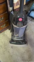 Front view of Hoover TurboPower 4900 vacuum showing vacuum and hose attachment, black and gray with red Hoover logo