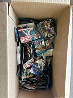 Box filled with hundreds of assorted sports trading cards piled loosely showing variety and quantity.