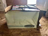 Large cardboard Bankers Box containing numerous comic books and graphic novels, some stacked and some loosely placed, indicating a big mixed collection primarily of Archie Comics.