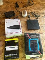 Full view of all items included in the electronics bundle showing DVD writer, RAM, cassette player, Garmin device and router with their boxes and cables.