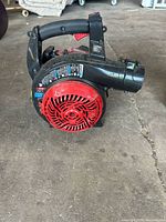 Side view of the blower showing red air intake cover and black handle with trigger control