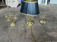 Full set including the brass lamp with black shade, five-arm candelabra, and single candle holder on concrete floor.