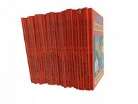 Side view showing 27 hardcover books with bright red spines lined up, titles and volume numbers visible.