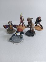 Image showing five Disney Infinity figures including Black Widow, Jack Sparrow, Rocket Raccoon, Anakin Skywalker, and Ahsoka Tano from front view.
