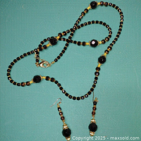 Necklace and dangle earrings laid flat on teal background, showing details of bead placement and clasps.