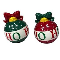 Two ceramic Christmas ball salt and pepper shakers side by side, showing green with red bow and red with green bow, both with 'HO HO HO' lettering