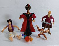 Five plastic action figures of characters from Aladdin and Shrek photographed together on white background.