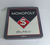 Front view of the Monopoly Nostalgia Edition collectible tin with logo and design visible.