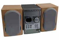 Front view of Philips MCM530 stereo system main unit flanked by two wooden speakers with grey fabric covers.