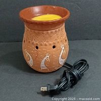 Full-size terracotta wax warmer with painted Kokopelli figures, yellow wax in glazed removable top dish, and attached electric power cord with two-prong plug.