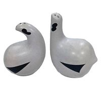 Pair of white ceramic salt and pepper shakers shaped like abstract ptarmigan birds with black geometric patterns, side view showing shape and holes for sprinkling.