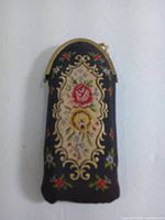 Front of embroidered petit point flask case showing floral embroidery and brass top
