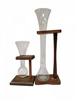 Two vintage yard ale glasses with wooden stands shown front view on white background. Smaller quarter yard glass on left and taller half yard glass on right.