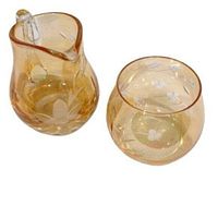 Amber glass sugar bowl and creamer set with etched floral patterns visible, showing overall condition and design