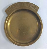 Top side of the vintage solid brass pocket change tray showing 'POCKET CHANGE' engraving and aged brass surface.