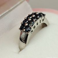 Close-up image of the silver ring showing the blue sapphire stones and prong setting on top of the band.