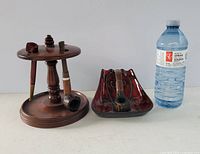 Photo showing two smoking pipe holders and three vintage smoking pipes alongside a water bottle for scale.