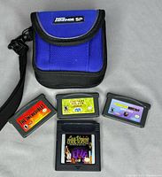 Photo showing blue nylon carrying case and four game cartridges for Game Boy Advance and original Game Boy