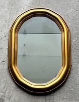 Front view of large oval mirror with gold plastic frame showing entire item and surrounding floor surface.