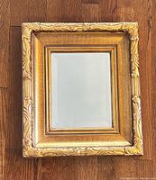 Full view of the ornate gilt mirror showing the entire frame and beveled glass.