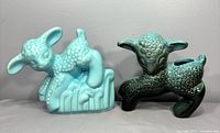 Pair of ceramic baby sheep planters shown from front on grey background, blue one on left and black-green swirl on right