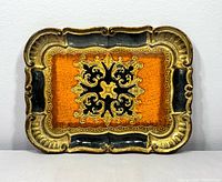 Front view of the small vintage Italian Florentine tray showing ornate scalloped edges and detailed gold and black painted design on burnt orange background.