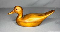 Front-side angle showing smooth wooden texture and eye detail of the carved pintail duck