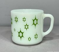 Side view of vintage Federal milk glass mug with green starburst designs on opaque white glass.