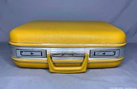 Front view of vintage yellow hard shell travel case showing two combination locks and handle