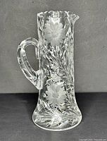Front view of the large crystal pitcher showing etched daisies design, thick handle and scalloped rim.