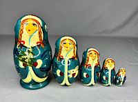 Front view of 5 vintage Russian nesting dolls with blue coats and braided hair