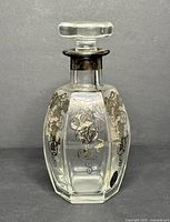 Photo of the entire vintage glass decanter with silver overlay, stopper in place, showing overall shape and design.
