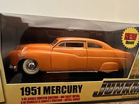 Front and side view of the 1951 Mercury model car in original box showing orange color and clear display window.