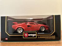 Front view of red 1988 Lamborghini Countach model in original Burago packaging, displayed in a clear window box with black and gold branding.